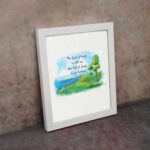 Psalm 46:7 Bible verse wall art with serene watercolor landscape of trees, hills, and water, featuring the verse in black text. displayed on the wall in a white frame