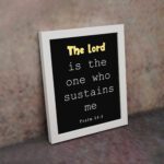 Psalm 54:4 Bible Verse Wall Art - The Lord Is The One Who Sustains Me in bold text on a black background for Christian home decor. Wall Art displayed on the wall in a white frame