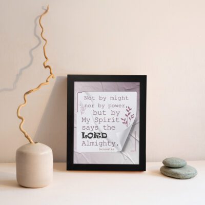 Zechariah 4:6 Bible verse wall art with soft purple text, bold LORD, decorative plant motif, and light purple folded paper background. displayed on the wall in a black frame