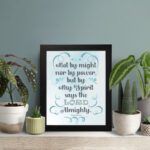 Zechariah 4:6 Bible verse wall art with light blue and white text, decorative flourishes, and a light blue gradient background. Inspiring Christian home decor. Wall Art on the displayed table in a black frame