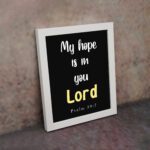 Psalm 39:7 Bible verse wall art with a black background, Lord in yellow. Christian home decor by Infidu. Wall Art kept on the wall in a white frame