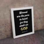 Bible verse wall art with black background, yellow and white font, featuring Matthew 5:8 verse white frame on the wall