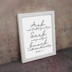 Matthew 7:7 Bible wall art in elegant cursive, highlighting Ask, Seek, and Knock on a white background. displayed on the wall in a white frame