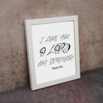 I LOVE YOU O LORD MY STRENGTH black handwritten text on a light background with Psalm 18:1 - Christian wall art for home decor. displayed on the wall in a white frame