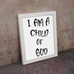 I Am a Child of God Bible wall art with bold black text on a white background, framed by a subtle black border. Wall Art displayed on the wall in a white frame