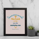 Surely God Is My Help - Psalm 54:4 Bible Verse Wall Art with Colorful Fonts and Cross Symbol on Soft light pink Background Wall Art displayed on the wall in a black frame