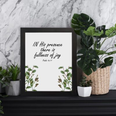 In His Presence There Is Fullness of Joy - Psalm 16:11 Bible Verse Wall Art with Green Leaf Design on White Background Wall Art displayed on the table in a black frame