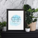 Serene Bible verse wall art with Psalm 2:12 and soft blue watercolor design, perfect for peaceful home decor. Wall Art displayed on the table in a black frame