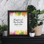 Vibrant Bible wall art with Psalm 2:12 verse and colorful paint splash in green, yellow, pink, and orange. Wall Art displayed on the table in a black frame