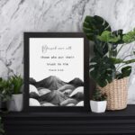 Psalm 2:12 Bible wall art featuring a black-and-white mountain landscape with the verse Blessed are all those who put their trust in Him. Wall Art displayed on the table in black frame