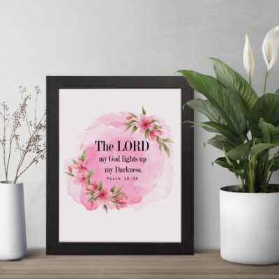 The Lord My God Lights Up My Darkness Psalm 18:28 Bible Verse Wall Art with black text on a soft pink watercolor background and delicate floral accents. Wall Art displayed on the table in a black frame