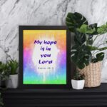 Infidu My Hope Is In You Lord Psalm 39:7 Bible Wall Art with bright blue and pink text and colorful watercolor background Wall Art displayed on the table in a black frame