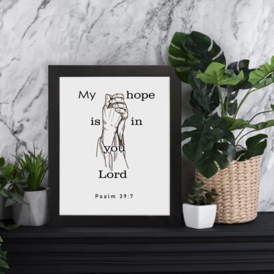 Infidu My Hope Is In You Lord Psalm 39:7 Bible Wall Art with a minimalist line drawing of figure in prayer and clean text Wall Art displayed on the table in a black frame