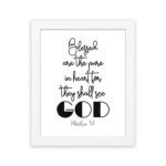 Infidu wall art with the text Blessed is the pure in heart, for they shall see God in black font on a white background. hung on the wall in a white frame