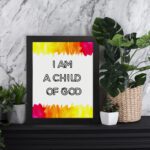 Infidu I Am A Child Of God Bible Wall Art with colorful watercolor borders and black block text on a white background Wall Art displayed on the table in a black frame