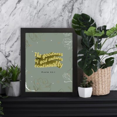 Psalm 52:1 wall art with gold God text and subtle floral patterns on a soft gray background. Wall Art displayed on the table in black frame