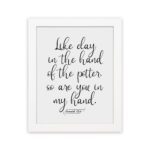 Infidu wall art with the text Like clay in the hand of the potter, so are you in my hand in decorative and standard fonts, black on white background. hung on the wall in a white frame