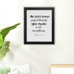 Infidu wall art with the text Be joyful always, pray continually, give thanks in all circumstances from 1 Thessalonians 5:16-18. hung on the floor in a black frame