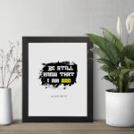 Be Still and Know That I Am God Psalm 46:10 Christian wall art with handwritten text on a navy blue background. Wall Art displayed on the table in a black frame