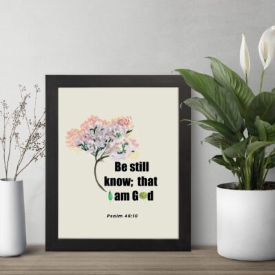 Be Still and Know That I Am God Psalm 46:10 Bible verse wall art with tree graphic, black and green text on a white background. displayed on the table in a black frame