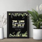 The Lord of Hosts is With Us Psalm 46:7 Bible Verse Wall Art with green leaves and bold cream and white text. displayed on the table in a black frame