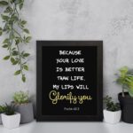 Psalm 63:3 Bible verse wall art with a dark background and cursive Glorify You in light gold. Christian home decor by Infidu. Wall Art displayed on the wall