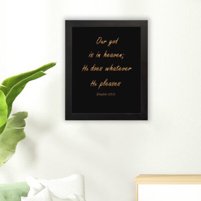 Bible verse wall art with Psalm 115:3 in gold text on a black background. Simple, elegant font centered for easy readability. hung on the floor in a black frame