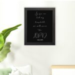 Joshua 24:15 Bible wall art with white cursive text on a black background, emphasizing LORD in a modern design. hung on the floor in a black frame