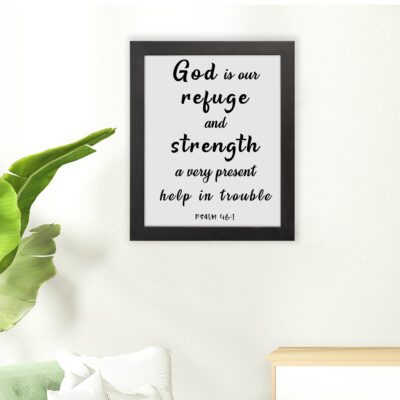 Psalm 46:1 Bible wall art with black bold text on a white background, saying 'God is our refuge and strength, a very present help in trouble. Wall Art hung on the floor in a black frame