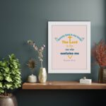 Surely God Is My Help - Psalm 54:4 Bible Verse Wall Art with Colorful Fonts and Cross Symbol on Soft light pink Background Wall Art hung on the wall in a white frame