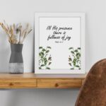 In His Presence There Is Fullness of Joy - Psalm 16:11 Bible Verse Wall Art with Green Leaf Design on White Background Wall Art displayed on the table in a white frame