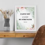 Infidu I Love You O Lord My Strength Psalm 18:1 Bible Wall Art with a green floral background and pink flowers Wall Art displayed on the table in a white frame