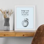 Keep Me As The Apple Of Your Eye Psalm 17:8 Bible Verse Wall Art with light blue background and simple apple sketch. Wall Art displayed on the table in a white frame