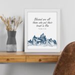 Psalm 2:12 Bible Verse Wall Art with deep blue mountain range design. Wall Art displayed on the table in a white frame