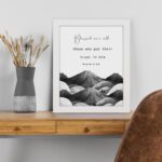 Psalm 2:12 Bible wall art featuring a black-and-white mountain landscape with the verse Blessed are all those who put their trust in Him. Wall Art displayed on the table in white frame