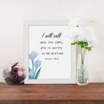 I Will Call Upon The Lord Psalm 18:3 Bible Verse Wall Art with black text on a light background and a soft blue flower in the bottom left corner. Wall Art displayed on the table in a white frame