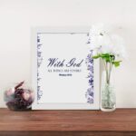 With God All Things Are Possible Matthew 19:26 Bible Verse Wall Art with blue text and watercolor-style floral border on a white background. Wall Art displayed on the table in a white frame