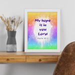 Infidu My Hope Is In You Lord Psalm 39:7 Bible Wall Art with bright blue and pink text and colorful watercolor background Wall Art displayed on the table in a white frame