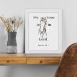 Infidu My Hope Is In You Lord Psalm 39:7 Bible Wall Art with a minimalist line drawing of figure in prayer and clean text Wall Art displayed on the table in a white frame