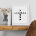 Infidu Jesus Loves Me Bible Wall Art with the crossword-style layout in black text on a white background Wall Art displayed on the table in white frame