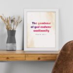 The Goodness Of God Endures Continually Psalm 52:1 Christian Wall Art with bold black and red text on a light cream background. Wall Art displayed on the table in a white frame