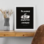 Infidu The Goodness Of God Endures Continually Psalm 52:1 Christian wall art with bold white text on a black background. Wall Art displayed on the table in a white frame