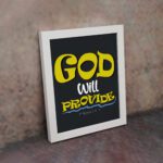 God Will Provide Christian wall art with bold yellow text and a dark black background, perfect for home decor. Wall Art displayed on the wall in a white frame