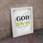 God Will Provide Christian wall art with bold black 'God,' gray and yellow text, and a heart-like light gray background. Wall Art displayed on the wall in a white frame