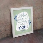 Infidu Matthew 5:8 Christian wall art with silver and dark blue text on a pale green background, featuring 'GOD' in a white oval and blue floral designs. Wall Art displayed on the wall in a white frame