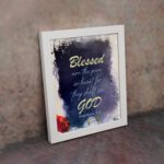 Infidu Matthew 5:8 Christian wall art with yellow text on a dark blue textured background, featuring bright yellow 'GOD' and a hint of red floral design. Wall Art displayed on the wall in white frame