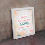 Infidu Isaiah 60:22 Christian wall art with coral and teal text, teal LORD, and a soft pastel watercolor background with floral shapes. Wall Art displayed on the wall in a white frame