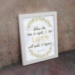 Infidu Isaiah 60:22 Christian wall art with green and gold text, gold LORD, and a wreath of green leaves on a white background. Wall Art displayed on the wall in a white frame