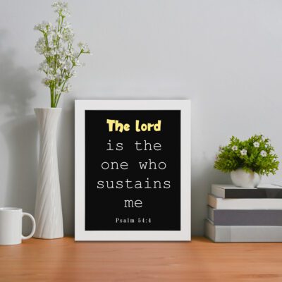 Psalm 54:4 Bible Verse Wall Art - The Lord Is The One Who Sustains Me in bold text on a black background for Christian home decor. Wall Art displayed on the table in a white frame