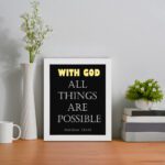 Matthew 19:26 Bible verse wall art with bold text, WITH GOD in yellow on a black background. Christian decor by Infidu. Wall Art displayed on the table in a white frame